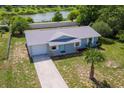 Aerial view of a single-story light gray home with an adjacent lake in a quiet neighborhood at 4 Kristin Ln, Eustis, FL 32726
