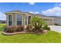 Attractive home with well-kept lawn and landscaping, including palm trees, shrubs, and stone-lined flower beds at 4346 Pezzullo Cir, The Villages, FL 32163