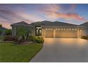Charming single-story home with a well-manicured lawn, lovely landscaping, and a spacious driveway at sunset at 4346 Pezzullo Cir, The Villages, FL 32163