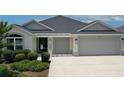 Front of a lovely one-story home with a well-maintained lawn and two-car garage at 6301 Danielson Loop, The Villages, FL 32163