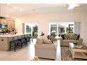 Open-concept living room with kitchen island, seating, and sliding doors to the patio at 6301 Danielson Loop, The Villages, FL 32163