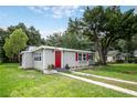 Lovely single story home featuring a red door, tidy landscaping, and mature trees at 780 N Kentucky Ave, Umatilla, FL 32784