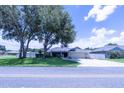 Inviting single-story home with lush front lawn, mature trees, and a spacious driveway leading to the garage at 8489 Se 158Th Pl, Summerfield, FL 34491