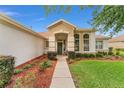 Inviting front entrance with a decorative wreath, vibrant plants and a well-maintained lawn at 9588 Se 124Th Loop, Summerfield, FL 34491