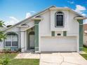 A white and green two-story home with a two-car garage features manicured landscaping and an inviting entrance at 1034 Copenhagen Way, Winter Garden, FL 34787