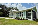 Light green house with white trim, screened in porch, and manicured landscaping at 12110 Grand Oak Ln, Oxford, FL 34484