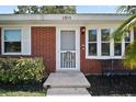 Close-up of a red brick house with a decorative front door and well-maintained garden at 1301 Cambridge Dr, Leesburg, FL 34748