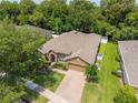 Aerial view of a well-maintained home with a lush lawn, driveway, and mature trees at 1556 Blue Grass Blvd, Deland, FL 32724