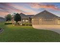 Inviting exterior of a home featuring a two-car garage and manicured front lawn at dusk at 17355 Se 110Th Ter, Summerfield, FL 34491
