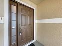 Close-up of the front door featuring a sidelight, hardware, and a fresh coat of brown paint at 2019 Newtown Rd, Groveland, FL 34736