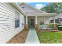Covered front porch with green door, classic brick accents, and well maintained landscaping at 25025 Cranes Roost Cir, Leesburg, FL 34748