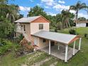 Two-story home with a carport and stairway, surrounded by lush greenery and mature trees at 27113 Robertson Rd, Yalaha, FL 34797
