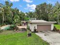 View of charming home featuring a pool, garage, and beautiful landscaping with a purple front door at 27113 Robertson Rd, Yalaha, FL 34797