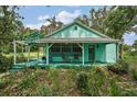 Charming blue cottage with a covered porch and cozy seating, nestled amongst mature greenery at 27113 Robertson Rd, Yalaha, FL 34797