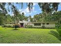 Sprawling one story house with green lawn, shrubbery, and established shade trees at 27113 Robertson Rd, Yalaha, FL 34797