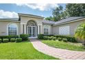 Beautiful home with landscaped yard, brick walkway, and a striking arched entryway at 29152 David Ct, Tavares, FL 32778