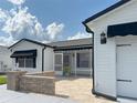 This home's front exterior offers a welcoming curb appeal with its light paint, brick accents, and screened-in porch at 3237 Atwell Ave, The Villages, FL 32162