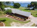 Lakefront brick home with a well-manicured lawn and lush landscaping, capturing serene waterfront living at 38314 Echols Rd, Leesburg, FL 34788