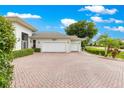 Multi-car garage and meticulously designed brick driveway, framed by verdant shrubs and swaying palm trees at 39145 Treeline Dr, Lady Lake, FL 32159