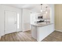 Bright kitchen featuring granite countertops, stainless steel appliances, and light wood flooring that leads to the front door at 4157 Tiedemann Loop, The Villages, FL 32163