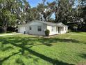 A single story home with white siding, a well manicured lawn and a detached garage at 460 Wisteria Ave, Umatilla, FL 32784