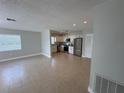 An open living room and kitchen area featuring tile flooring and stainless steel appliances at 460 Wisteria Ave, Umatilla, FL 32784
