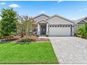Beautiful single-story home with paver driveway, lush landscaping, and gray-and-white exterior design at 5019 Ne 125Th Loop, Oxford, FL 34484
