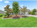 Front yard featuring mature trees, plants, mulch beds, and well-maintained lawn creating a picturesque landscape at 5019 Ne 125Th Loop, Oxford, FL 34484