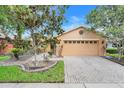 Charming single-Gathering home featuring a two-car garage, a brick paver driveway, and meticulously maintained landscaping at 645 Highlands Hammock Dr, Kissimmee, FL 34759