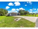 Attractive single-story home with a long driveway, complemented by green grass and blue skies with puffy white clouds at 70 Locust Pass Run, Ocala, FL 34472