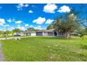 A lovely one-story home with green front lawn, mature trees, and clear blue sky, situated on a spacious lot at 70 Locust Pass Run, Ocala, FL 34472
