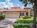 Charming exterior showcasing a barrel tile roof, arched windows and a two-car garage at 9335 San Jose Blvd, Howey In The Hills, FL 34737