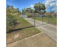 View of home with long driveway and gated yard, enhanced by mature trees and flowering bushes at 100 W Idlewild Ave, Eustis, FL 32726