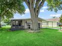 Well-maintained single-story home with a covered carport and a screened-in porch surrounded by lush green lawn at 1005 Richard Dr, The Villages, FL 32159