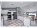 Open kitchen with stainless appliances, breakfast bar, laminate flooring, and seamless flow into living area at 1132 Hill Mount Dr, Minneola, FL 34715