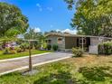 Single-story home with a well-manicured lawn, mature landscaping, and a convenient carport in a serene setting at 1156 Capella Dr, Tavares, FL 32778
