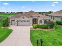 Single-story home with a well-maintained lawn, attached two-car garage, and manicured landscaping at 12198 Se 176Th Loop, Summerfield, FL 34491