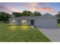 Attractive single-story home with an attached garage under a colorful evening sky at 14611 Se 95Th Ct, Summerfield, FL 34491