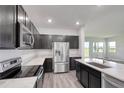 Modern kitchen featuring stainless steel appliances, dark cabinetry, and a quartz countertop island, with wood flooring at 1696 Wilson Prairie Cir, Groveland, FL 34736