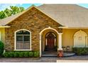 Charming front entrance of a home featuring stone accents, arched doorway, and manicured landscaping at 18008 Victorian Dr, Clermont, FL 34715