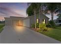 Home exterior showing the driveway, carport, and well-lit landscape at dusk at 1815 Kaufman Cir, Lady Lake, FL 32159