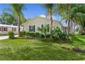 Home featuring a well-manicured lawn, complemented by lush landscaping and mature palm trees at 1815 Kaufman Cir, Lady Lake, FL 32159