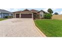 Charming single-story home featuring a beautifully landscaped front yard, patterned driveway, and a three-car garage at 2585 Constance Ct, The Villages, FL 32163