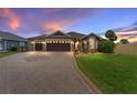 Charming single-story home featuring a beautifully landscaped front yard, patterned driveway, and a three-car garage at 2585 Constance Ct, The Villages, FL 32163