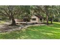 Charming house exterior with a patio and expansive yard, surrounded by mature trees and greenery at 31136 Senese Rd, Sorrento, FL 32776