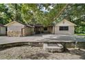 Quaint home with a large concrete patio, stone accents, and charming curb appeal surrounded by trees at 31136 Senese Rd, Sorrento, FL 32776
