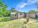 Spacious backyard with a storage shed, green grass and mature trees on a sunny day at 326 N Lancelot Ave, Orlando, FL 32835