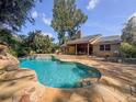 Backyard oasis featuring a sparkling pool with a rock waterfall and an outdoor dining area at 3664 Se 45Th Pl, Ocala, FL 34480