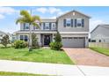 Two-story home showcasing beautiful landscaping, a brick driveway and neutral colored exterior at 391 Cheeota Ct, Minneola, FL 34715