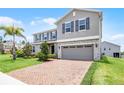 Two-story home with a brick driveway, lush green grass, and a neutral colored exterior at 391 Cheeota Ct, Minneola, FL 34715